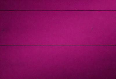 The primary subject of the image is a large, purple sheet of paper. The setting is a room with a pink background, which creates a warm and inviting atmosphere. The visual style is a close-up of the purple paper, emphasizing its texture and color. The colors and mood of the image are predominantly pink, giving it a soft and feminine appearance.
