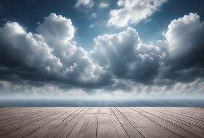 The primary subject of the image is a wooden deck with a cloudy sky in the background. The setting appears to be a beach or a similar outdoor location. The visual style of the image is a black and white photo, which adds a sense of nostalgia and timelessness to the scene. The dominant colors are shades of gray and white, with the wooden deck and the cloudy sky providing a contrasting backdrop. The overall atmosphere of the image is serene and contemplative, inviting the viewer to imagine