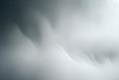 The primary subject of the image is a snowy mountain with a cloudy sky. The setting is a winter landscape, and the visual style is a photo. The dominant colors are white and gray, creating a cold and snowy atmosphere.