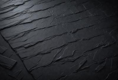 The primary subject of the image is a black leather surface with a textured, cracked appearance. The setting is a dark room, and the visual style is a close-up of the leather surface. The colors and mood of the image are predominantly dark and moody, with the black leather serving as the focal point.