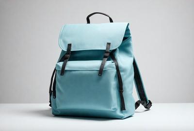 The primary subject of the image is a blue backpack. The backpack is placed on a white surface, which serves as the background. The visual style of the image is a photo, capturing the details of the backpack. The colors in the image are predominantly blue, giving the scene a calm and serene atmosphere.