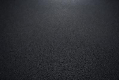 The primary subject of the image is a black carpeted floor. The setting is a dark room, and the visual style is a photo. The colors and mood of the image are dark and moody, with the black carpet and the dark room creating a sense of mystery and depth.