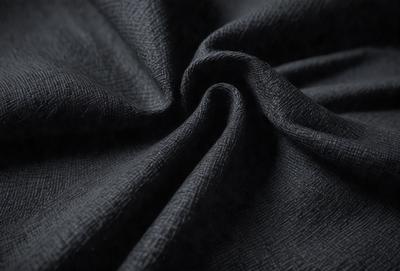 The primary subject of the image is a black fabric, possibly a piece of cloth or a curtain. The setting is a dark room, and the visual style appears to be a close-up of the fabric. The colors and mood of the image are predominantly dark and moody, with the black fabric being the main focus.