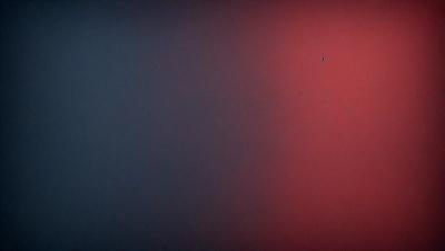 The primary subject of the image is a red wall with a blue background. The setting appears to be a room with a red and blue color scheme. The visual style of the image is a close-up of the red wall, which gives a sense of depth and texture. The dominant colors in the image are red and blue, creating a bold and vibrant atmosphere.