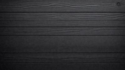 The primary subject of the image is a wooden wall. The setting is a dark room, and the visual style is a black and white photo. The colors and mood of the image are predominantly dark, creating a moody atmosphere.
