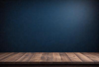 The primary subject of the image is a wooden table with a blue background. The table appears to be a part of a stage or a display area. The setting is a simple and clean environment, with no distractions or clutter. The visual style of the image is a combination of a photo and a digital art, giving it a unique and professional appearance. The dominant colors in the image are blue and brown, creating a calm and sophisticated atmosphere.
