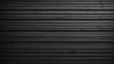 The primary subject of the image is a black and white photo of a wall. The setting is a black background, and the visual style is a close-up of the wall. The colors and mood of the image are predominantly black and white, creating a classic and timeless atmosphere.