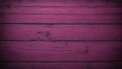 The primary subject of the image is a wooden wall with a purple color. The setting is a room with a wooden floor. The visual style is a close-up of the wooden wall, showcasing its texture and color. The dominant colors are purple and brown, creating a warm and cozy atmosphere.