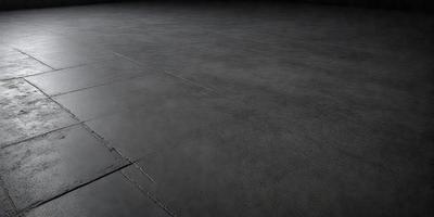 The primary subject of the image is a large, empty room with a grey floor. The setting is a dark room, possibly a basement, with a concrete surface. The visual style is a black and white photo, giving the image a classic and timeless appearance. The colors and mood of the image are predominantly dark and moody, with the grey floor and the overall atmosphere of the room contributing to this feeling.