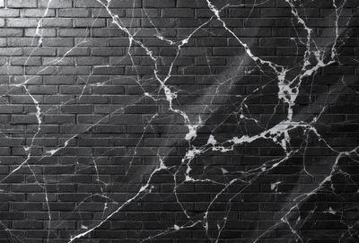 The primary subject of the image is a marble wall with a black brick background. The setting is a room with a brick wall, and the visual style is a close-up of the marble wall. The colors and mood of the image are predominantly black and white, giving it a classic and elegant appearance.