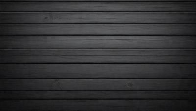 The primary subject of the image is a black wooden wall. The setting is a dark room, and the visual style is a black and white photo. The dominant colors are black and white, creating a moody atmosphere.