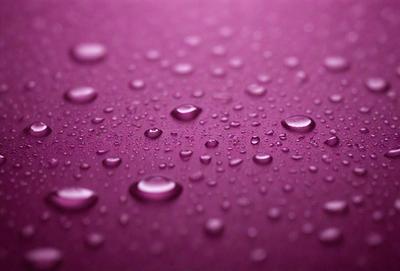 The primary subject of the image is a purple surface with water droplets on it. The setting is a purple background, and the visual style is a close-up of the purple surface with water droplets. The colors and mood of the image are predominantly purple, creating a calm and serene atmosphere.