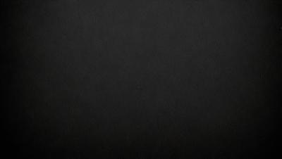The primary subject of the image is a black background. The setting is a dark room, and the visual style is a black and white photo. The colors and mood are dark and moody, creating a sense of mystery or drama.