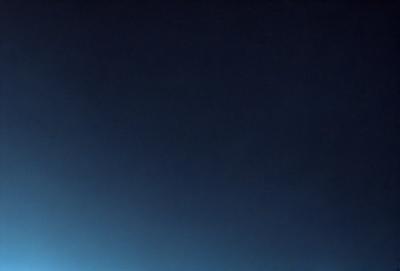 The primary subject of the image is the night sky, which is a dark blue color. The setting is a vast, open space with no visible landmarks or objects. The visual style is a natural, realistic representation of the night sky. The colors and mood convey a sense of tranquility and calmness, as the night sky is often associated with peacefulness and quietness.