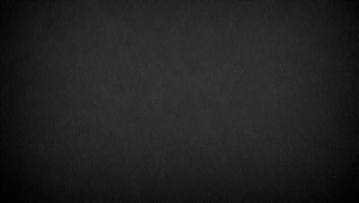 The primary subject of the image is a black background. The setting is a dark room, and the visual style is a black and white photo. The colors and mood of the image are dark and moody, creating a sense of mystery or drama.