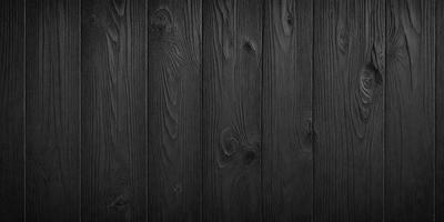 The primary subject of the image is a wooden wall with a black color. The setting is a room with a black background. The visual style is a black and white photo. The dominant colors are black and white, creating a moody atmosphere.