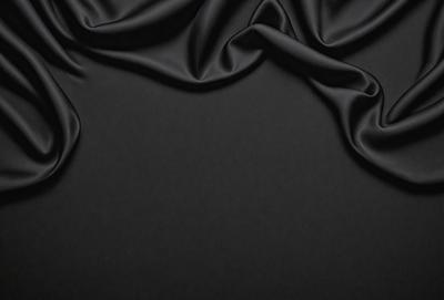 The primary subject of the image is a black fabric, which is the main object, scene, or focus of the image. The setting or background is a black surface, and the visual style is a photo. The colors and mood of the image are predominantly black, creating a dark and moody atmosphere.