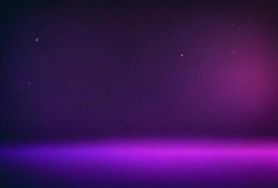 The primary subject of the image is a purple sky with a star visible in the background. The setting is a dark, purple-hued environment, which creates a moody atmosphere. The visual style appears to be a photo, as it captures the night sky with a star. The colors and mood of the image are predominantly purple, giving it a dramatic and mysterious feel.