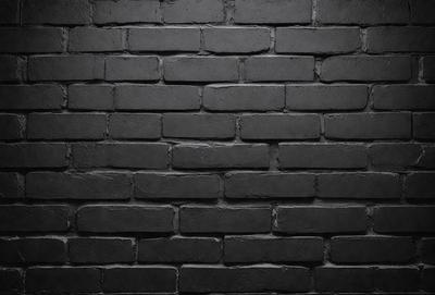 The primary subject of the image is a brick wall. The setting is a dark room, and the visual style is a black and white photo. The dominant colors are black and white, creating a moody atmosphere.