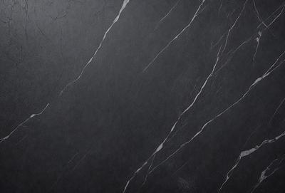 The primary subject of the image is a black marble countertop. The setting is a dark room, and the visual style is a close-up of the marble countertop. The countertop has a pattern of white lines, giving it a unique and elegant appearance. The colors and mood of the image are predominantly dark, with the black marble and white lines creating a striking contrast against the dark background.