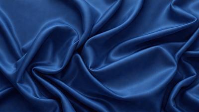 The primary subject of the image is a blue fabric, which appears to be a piece of silk. The setting is a close-up of the fabric, showcasing its texture and color. The visual style is a detailed, realistic representation of the fabric. The colors and mood of the image are predominantly blue, creating a calm and serene atmosphere.