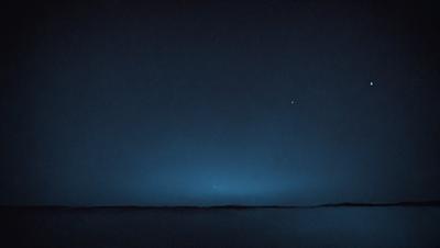 The primary subject of the image is the night sky, which is filled with stars. The setting is a dark, cloudy night, with the sky being the main focus of the image. The visual style is a photo, capturing the beauty of the night sky. The colors and mood of the image are predominantly dark and moody, with the stars and clouds creating a sense of mystery and wonder.