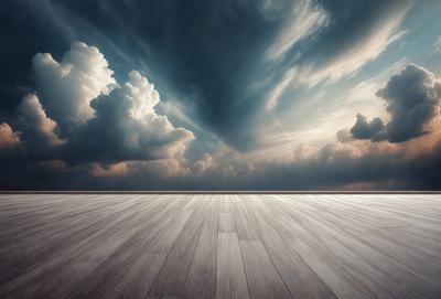 The primary subject of the image is a wooden floor with a cloudy sky in the background. The setting appears to be a large, open space with a sense of calmness. The visual style of the image is a black and white photo, which adds a timeless and classic feel to the scene. The dominant colors are shades of gray and black, creating a moody atmosphere.