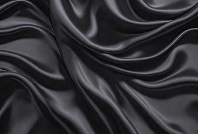 The primary subject of the image is a black fabric, which appears to be a piece of clothing or a curtain. The setting is a dark room, and the visual style is a close-up of the fabric. The colors and mood of the image are predominantly dark and moody, with the black fabric being the main focus.