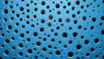 The primary subject of the image is a blue wall with a pattern of holes. The setting is a room with a blue background. The visual style is a close-up of the blue wall with a pattern of holes. The dominant colors are blue and white, creating a calm and soothing atmosphere.