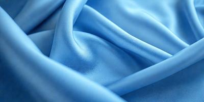 The primary subject of the image is a blue fabric, possibly a piece of leather, with a shiny texture. The setting is a close-up view of the fabric, showcasing its unique appearance. The visual style is a detailed, up-close representation of the fabric, highlighting its texture and color. The colors and mood of the image are predominantly blue, creating a calm and serene atmosphere.