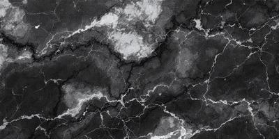 The primary subject of the image is a black and white marble wall with a pattern of white spots. The setting is a dark room, and the visual style is a close-up of the marble wall. The dominant colors are black and white, creating a moody atmosphere.