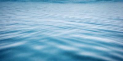 The primary subject of the image is a large body of blue water, which appears to be a lake or a large ocean. The water is calm and serene, with no visible waves or disturbances. The setting is a vast, open space, with no visible land or structures in the background. The visual style of the image is a realistic representation of the water, with no indication of digital art, illustration, or other manipulated elements. The colors and mood of the image are predominantly blue, creating a sense