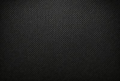 The primary subject of the image is a black background with a patterned texture. The setting is a dark room, and the visual style is a close-up of the patterned surface. The colors and mood of the image are predominantly dark and moody, with the black background and patterned texture creating a dramatic and intense atmosphere.