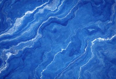 The primary subject of the image is a blue and white swirling pattern, which appears to be a blue marble or a blue and white tile. The setting is a blue surface, possibly a wall or a countertop. The visual style is a close-up of the swirling pattern, showcasing its intricate details. The colors and mood of the image are predominantly blue, with a touch of white, creating a serene and calming atmosphere.