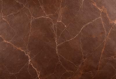 The primary subject of the image is a brown leather surface with a textured pattern. The setting is a close-up of the leather, showcasing its unique texture and appearance. The visual style is a realistic representation of the leather, capturing its natural beauty. The colors and mood of the image are warm and earthy, evoking a sense of richness and quality.