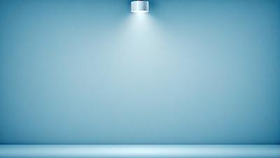 The primary subject of the image is a light source, which is shining brightly on a blue wall. The setting is a room with a blue wall, and the visual style appears to be a photo. The colors and mood of the image are predominantly blue, creating a calm and serene atmosphere.