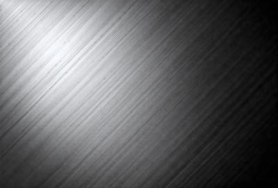 The primary subject of the image is a silver surface, which appears to be a metal wall or a shiny metal sheet. The setting is a black background, which contrasts with the silver surface. The visual style is a close-up of the silver surface, showcasing its texture and reflective properties. The colors and mood of the image are predominantly silver and black, creating a sleek and modern atmosphere.