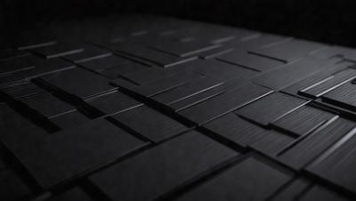 The primary subject of the image is a black and white patterned surface, which appears to be a tile or a piece of artwork. The setting is a dark room, and the visual style is a close-up of the patterned surface. The colors and mood of the image are predominantly black and white, creating a sense of depth and contrast.