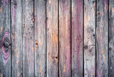 The primary subject of the image is a wooden wall with a variety of colors and textures. The setting is a room with a wooden wall, and the visual style is a close-up of the wooden wall. The dominant colors are red, brown, and purple, creating a warm and vibrant atmosphere.