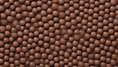 The primary subject of the image is a close-up of a chocolate-covered peanut. The setting is a brown surface, possibly a wall or a table, with a pattern of peanuts covering it. The visual style is a close-up of the chocolate-covered peanut, emphasizing its texture and details. The colors and mood of the image are predominantly brown, with the chocolate and peanut colors creating a warm and inviting atmosphere.