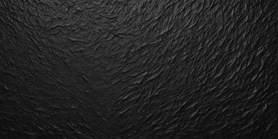 The primary subject of the image is a close-up of a black, textured surface. The setting appears to be a dark room, with the black surface being the main focus of the image. The visual style is a close-up of a textured surface, which gives the image a somewhat moody and mysterious atmosphere.