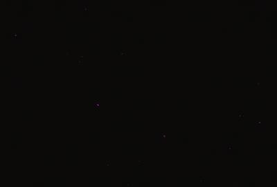 The primary subject of the image is a black background with a few purple stars scattered throughout the scene. The visual style appears to be a digital art or illustration, as the purple stars are the main focus of the image. The colors and mood of the image are predominantly dark and moody, with the purple stars adding a touch of brightness and contrast to the overall atmosphere.