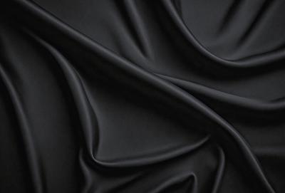 The primary subject of the image is a close-up of a black fabric, possibly a piece of clothing or a curtain. The setting is a dark background, which emphasizes the fabric's texture and pattern. The visual style is a close-up, which highlights the fabric's details. The colors and mood of the image are predominantly dark, with the black fabric being the main focus.
