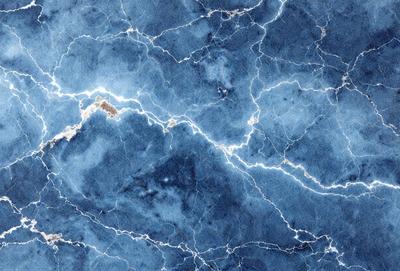 The primary subject of the image is a blue marble wall with a pattern of light and dark blue streaks. The setting is a room with a blue marble floor. The visual style is a close-up of the marble wall, showcasing the intricate pattern of the blue streaks. The colors and mood of the image are predominantly blue, creating a calm and serene atmosphere.