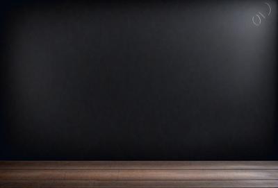 The primary subject of the image is a black wall with a wooden floor. The setting is a room with a wooden floor, and the visual style is a photo. The dominant colors are black and brown, creating a dark and moody atmosphere.