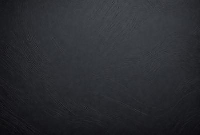 The primary subject of the image is a black background with a pattern of swirls. The setting is a dark room, and the visual style is a close-up of the pattern. The colors and mood of the image are predominantly dark and moody, with the swirls creating a sense of depth and intrigue.