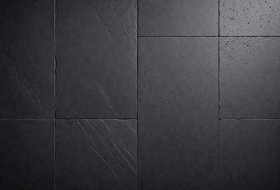 The primary subject of the image is a black tile floor. The setting is a dark room with a black tile floor, which is the main object of the image. The visual style is a photo, and the colors and mood are dark and moody.
