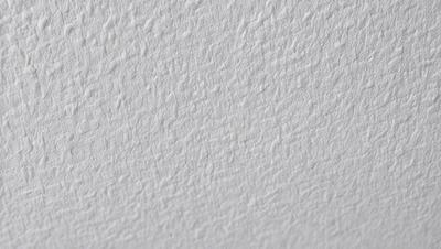 The image features a white wall with a textured surface. The primary subject is the wall, which appears to be a white painted surface with a patterned texture. The setting is indoors, and the visual style is a close-up of the wall. The colors and mood of the image are predominantly white, giving it a clean and minimalist appearance.