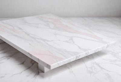 The primary subject of the image is a white marble table with a pink border. The table is placed on a white surface, which could be a table or a wall. The visual style of the image is a photo, showcasing the marble table and its pink border. The colors and mood of the image are predominantly white and pink, creating a clean and elegant atmosphere.