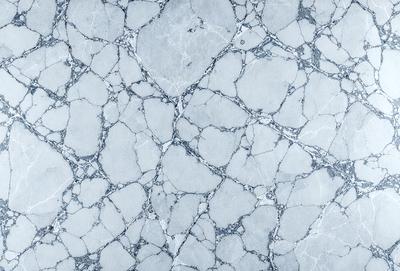 The image features a white marble surface with a pattern of holes and bumps. The primary subject is the marble, which is the main object, scene, or focus of the image. The setting is a white marble countertop, and the visual style is a photo. The colors and mood of the image are predominantly white, giving it a clean and elegant appearance.